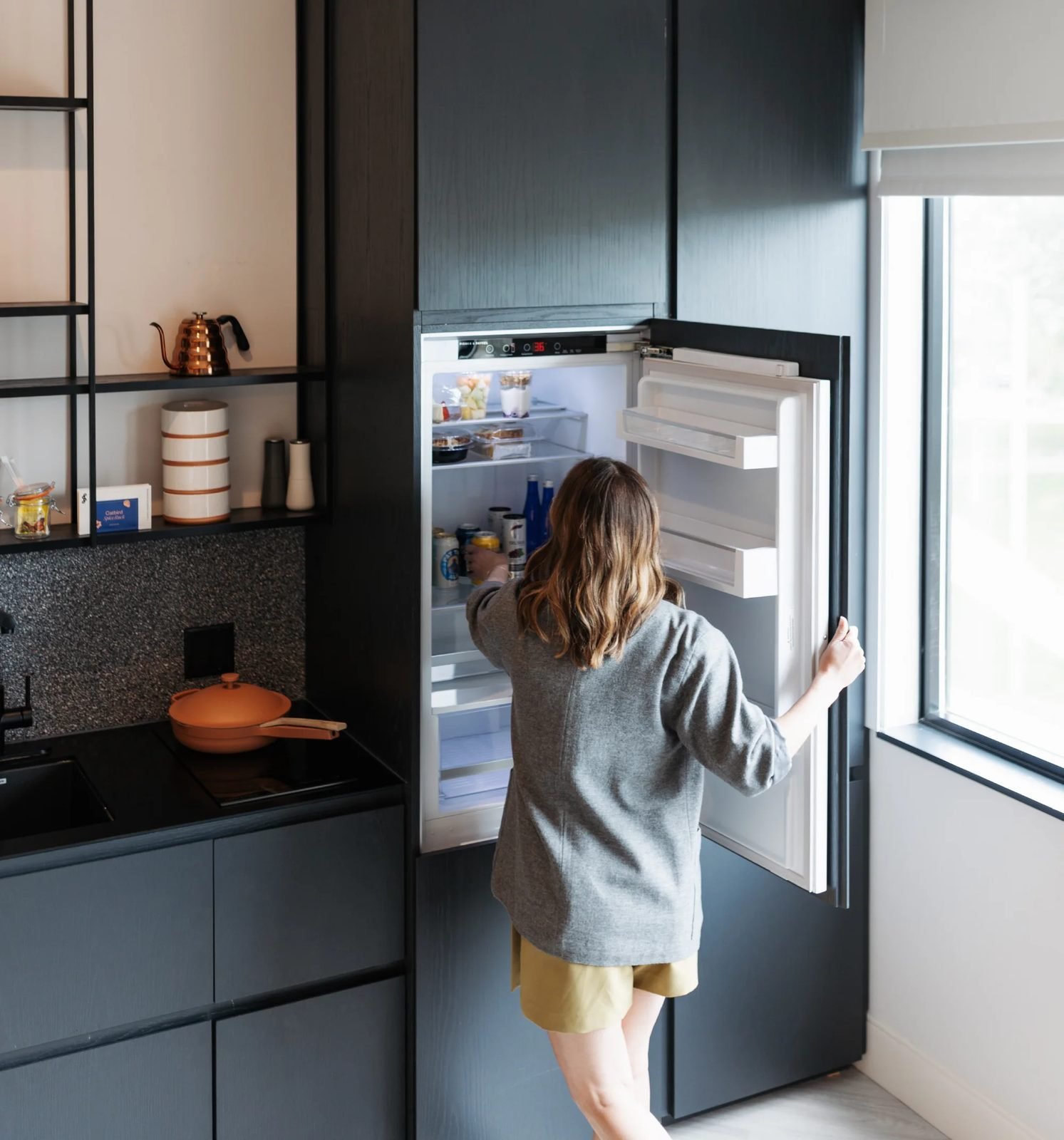 Guest reaching into the full kitchen in her room